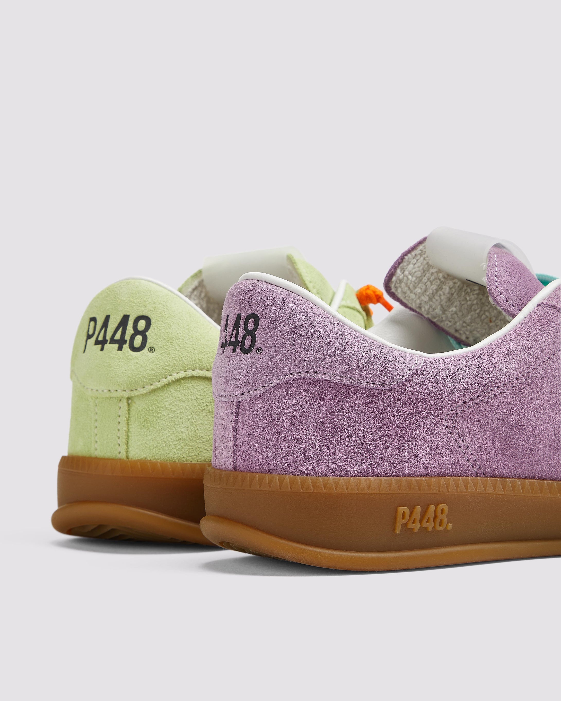 Side angle of the left green sneaker with orange laces and right purple sneaker with blue laces