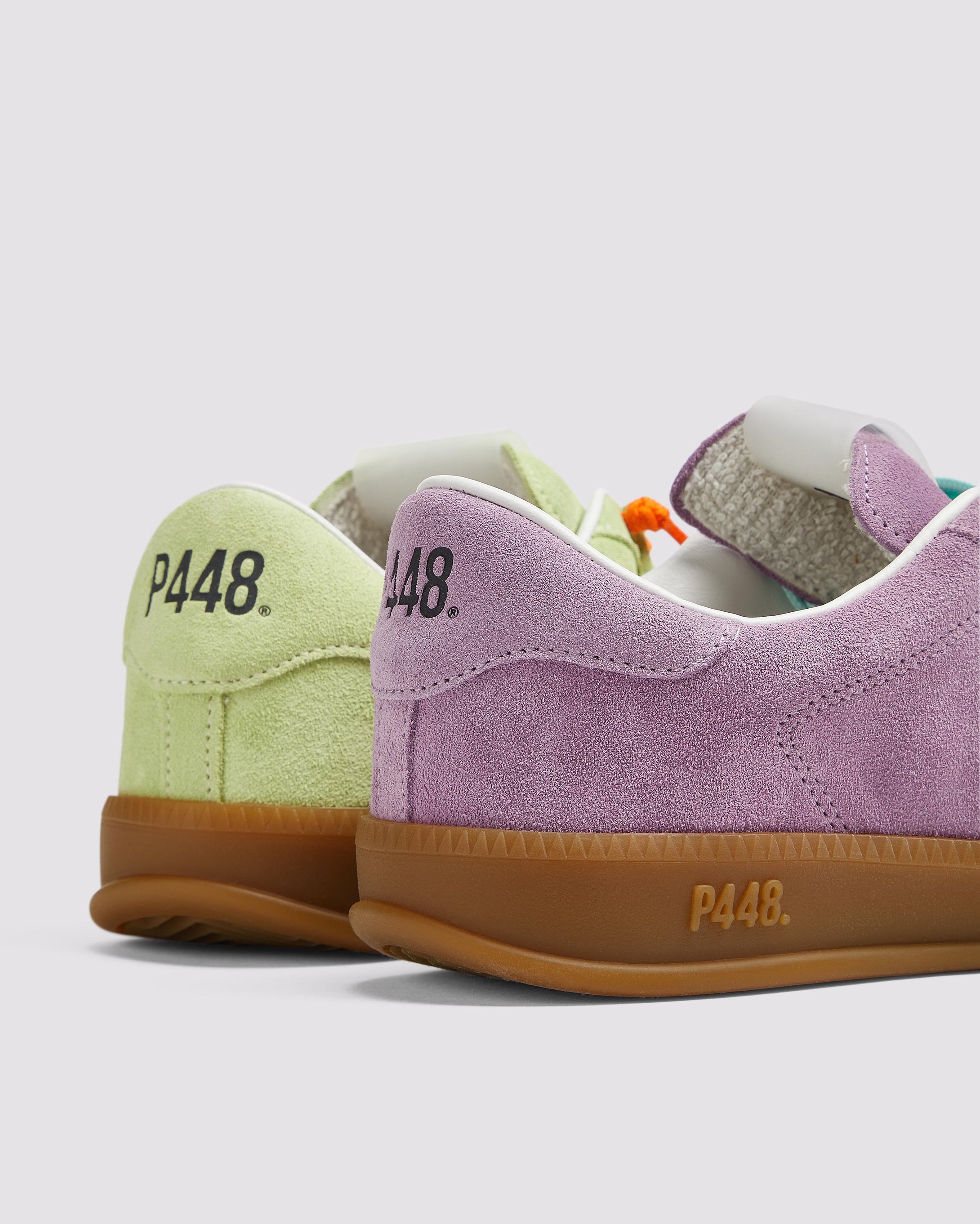 Side angle of the left green sneaker with orange laces and right purple sneaker with blue laces