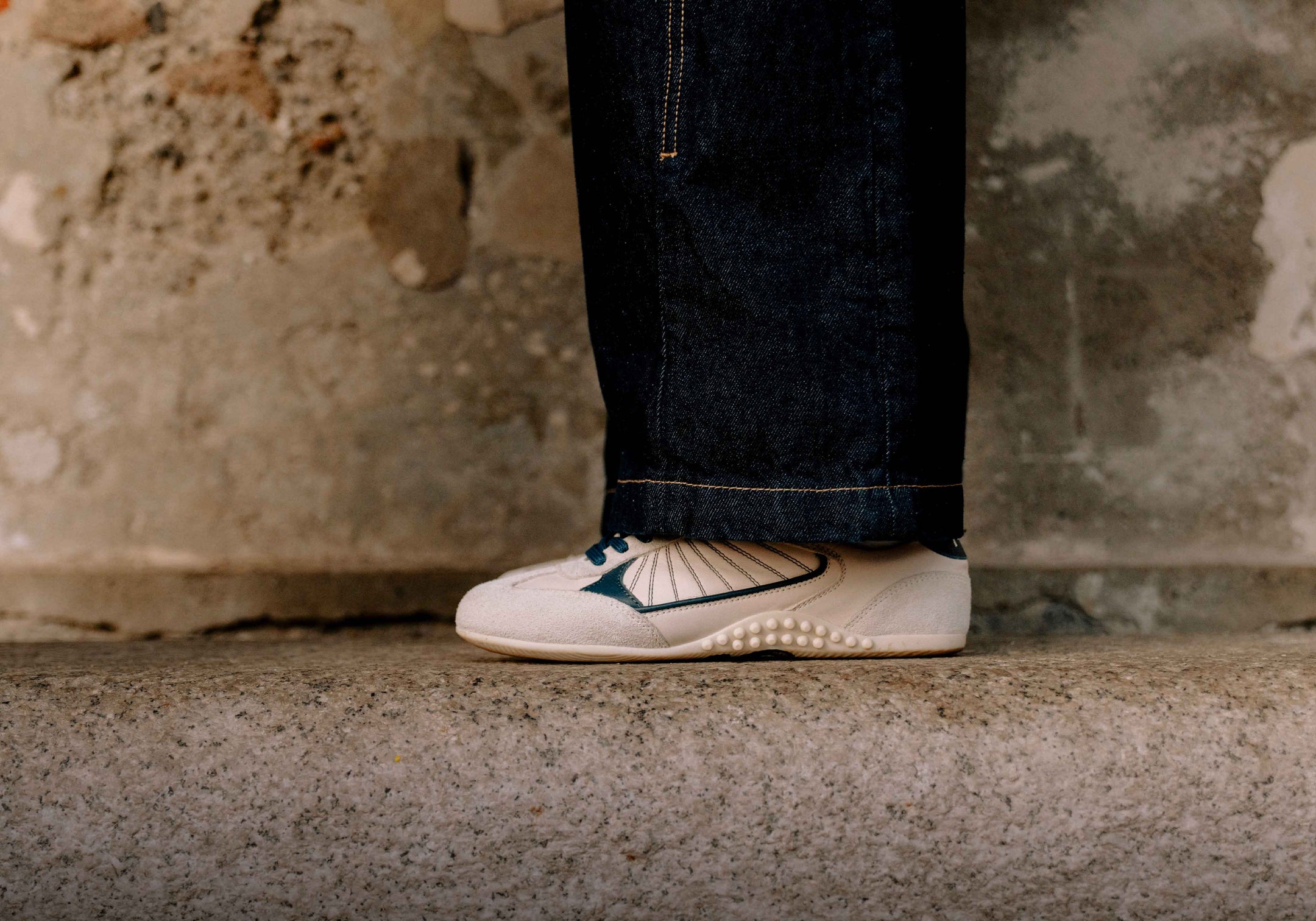 0815 off-white and teal sneakers paired with dark cuffed denim jeans.